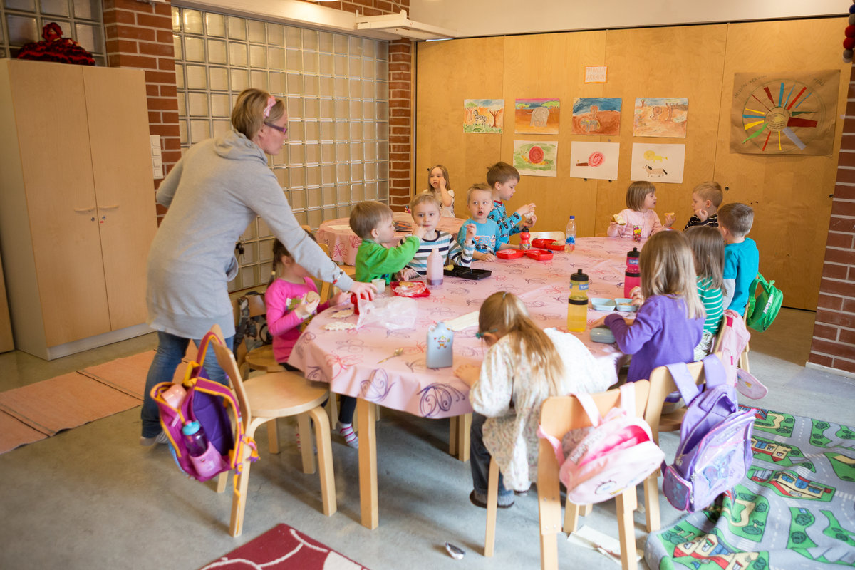 seurakunnan päiväkerhossa puuhastelua, lapsia pöydän ääressä ja ohjaaja